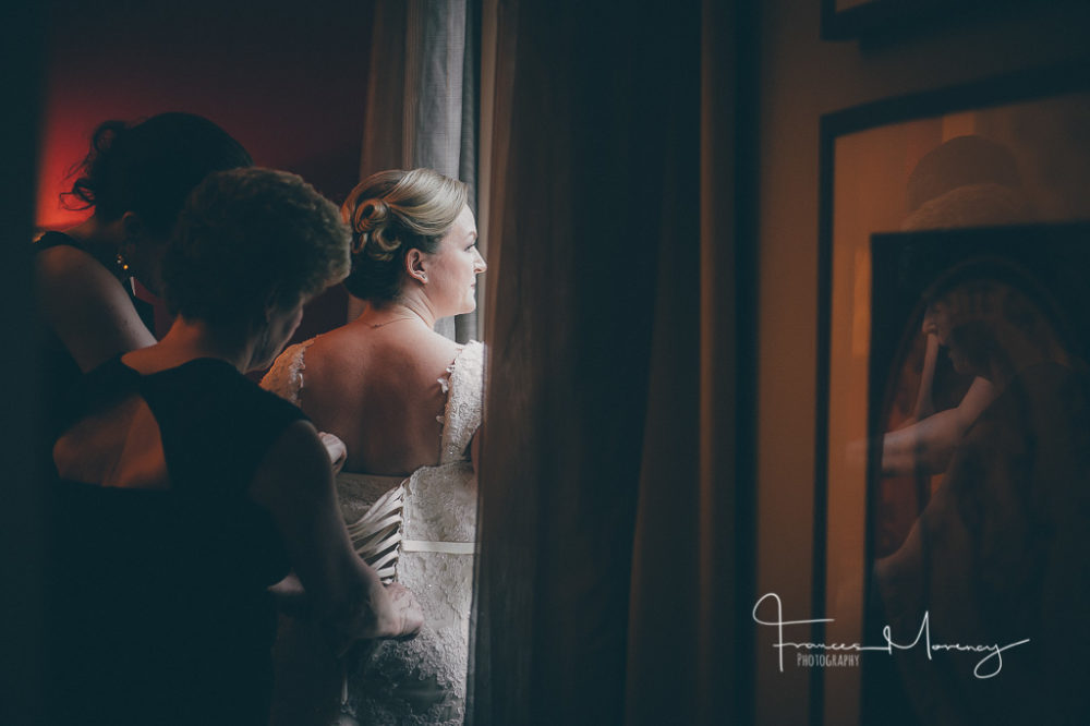 Lace corset gown in soft white is laced up by mom and maid of honour by the window light Collingwood Wedding Photographer-4666