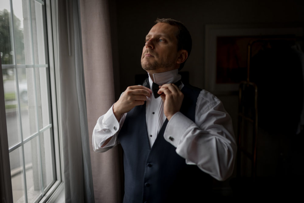 groom getting ready by window light groom getting ready by window light