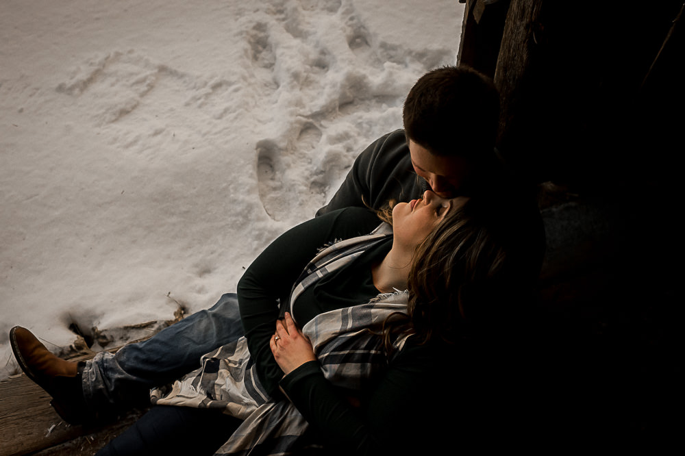 photos in a barn with engagement couple sitting on the floor