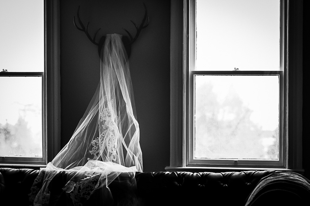 Black and white image of the veil hanging on antlers. Bridal preparations at The Farmhouse Restaurant in Barrie.