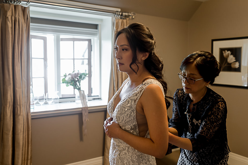 Mother helping bride in suite at Ancaster Mill