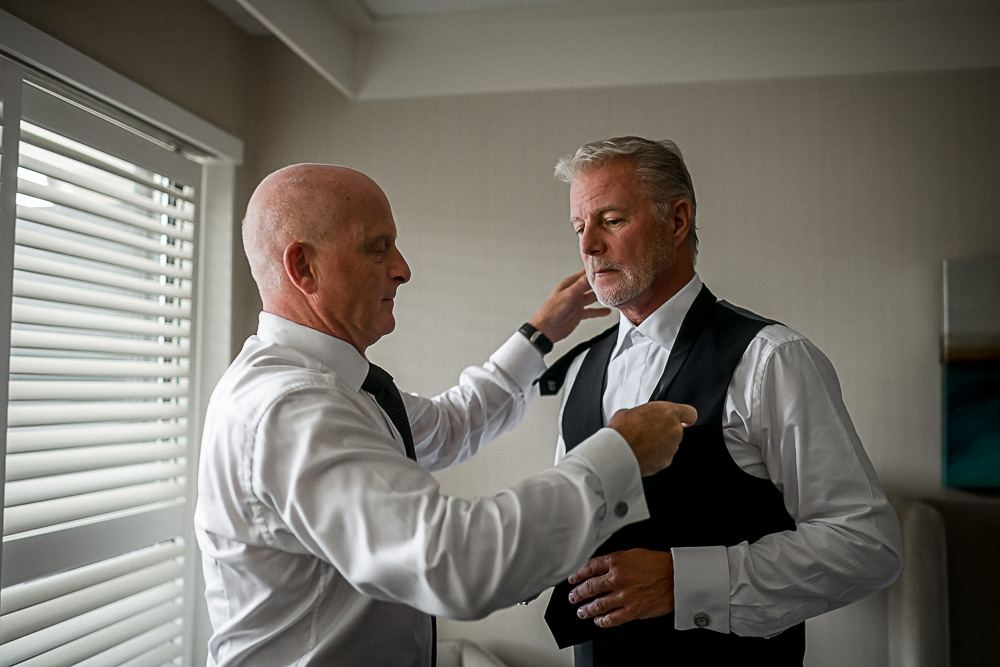 best man helping groom dress
