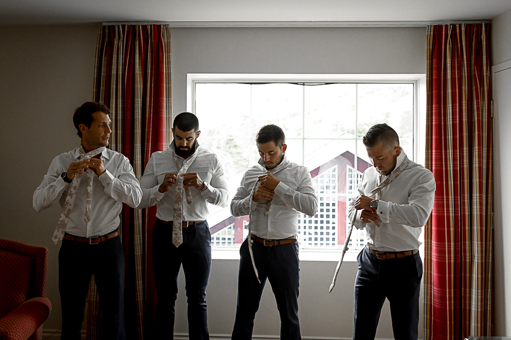 groomsmen putting on ties together