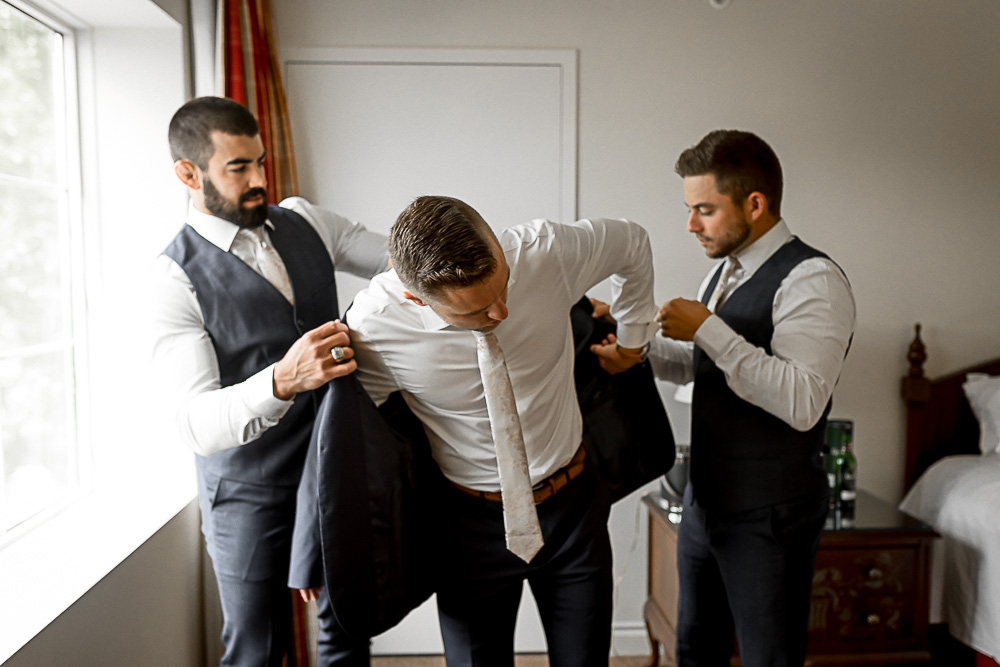 groomsmen getting groom dressed
