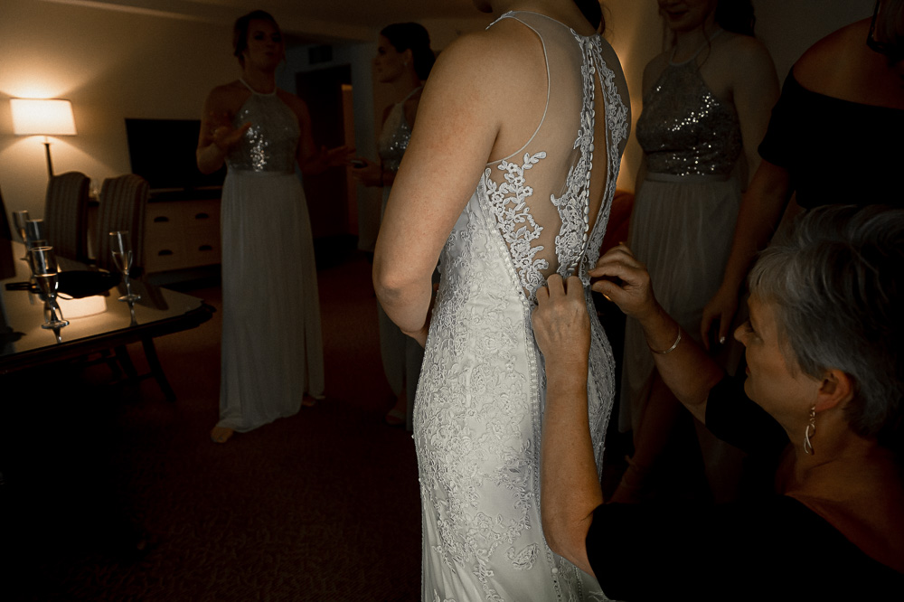 bride getting help with dress buttons