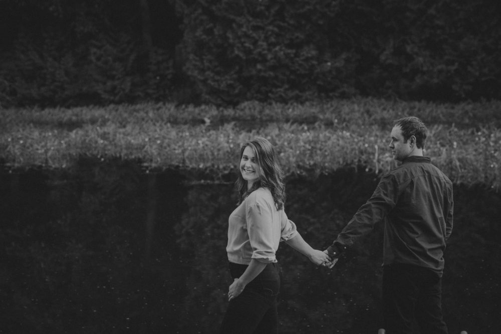 couple holding hands by pond