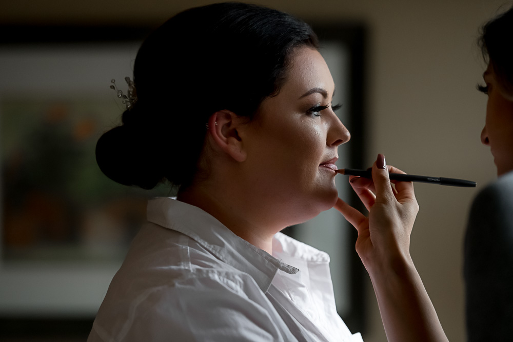 bride getting makeup done in chair