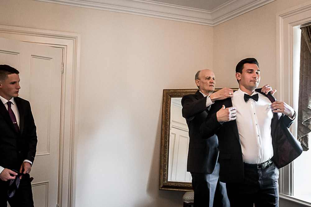 dad helps groom in jacket