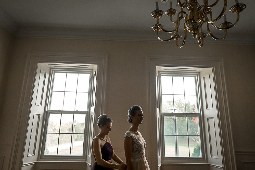 sister helps bride in gown