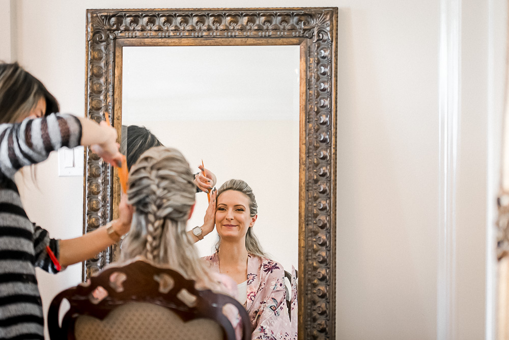 bride getting makeup done in reflection