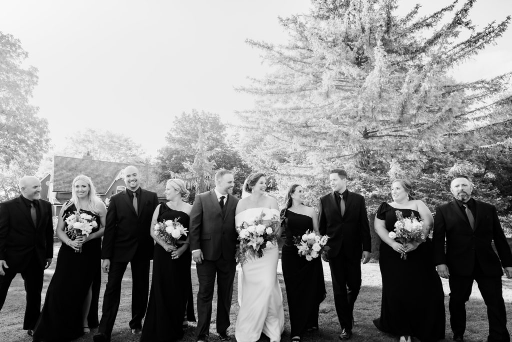 black and white photo of wedding party walking with back light