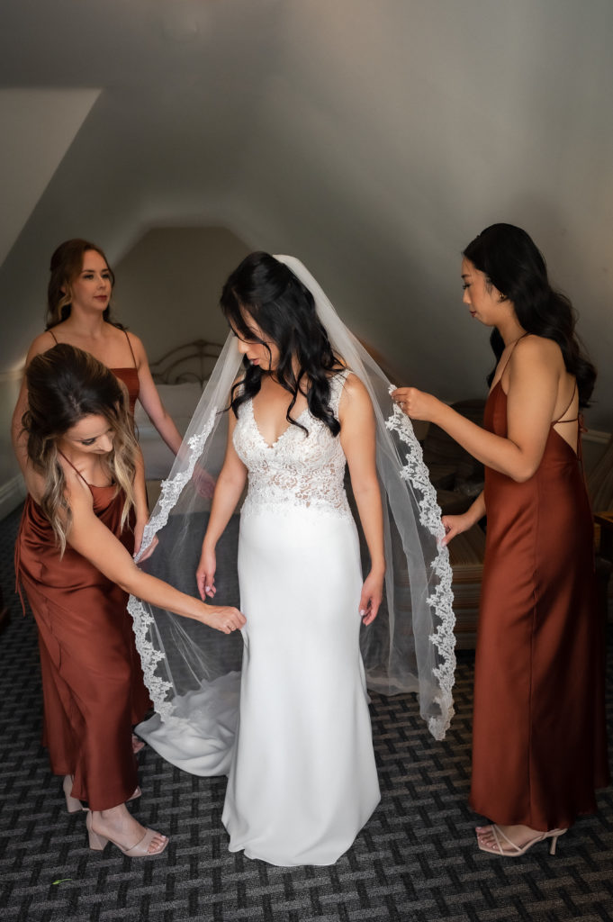 bridesmaids adjusting veil on bride