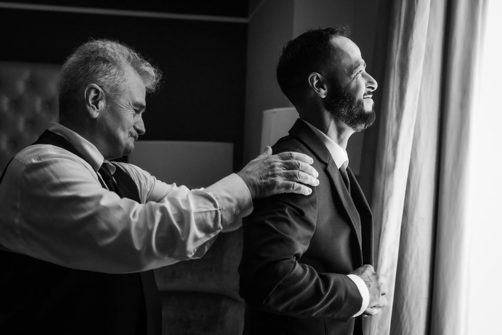 Dad helps groom put on suit jacket